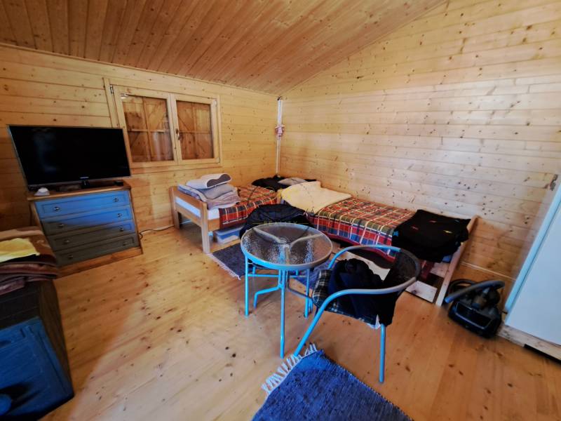 Ein Zimmer mit Wänden aus Holz, Betten, einem Fernseher und einem Boden mit Holzdekor.