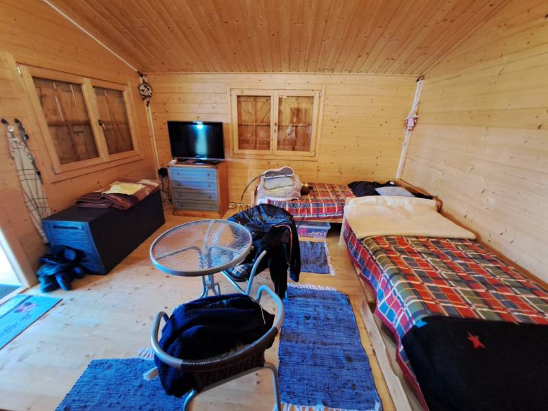 Ein Zimmer im Garten mit einem Tisch, Stühlen und zwei Betten mit bunten Decken.