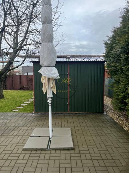 Gärten in Dolné Krškany in Nitra mit einem zusammengefalteten Sonnenschirm, befestigter Fläche und Rasen.