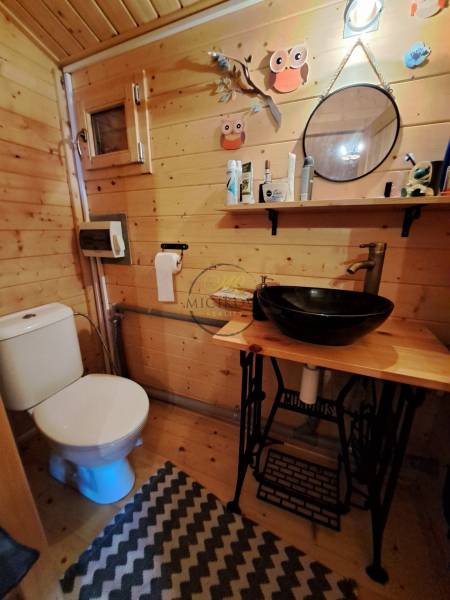 Holzinterieur eines Badezimmers mit Spiegel, Regal und Waschbecken in den Gärten.