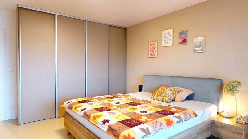 Schlafzimmer in einem Einfamilienhaus mit Bett, Einbauschrank und dekorativen Bildern an der Wand.