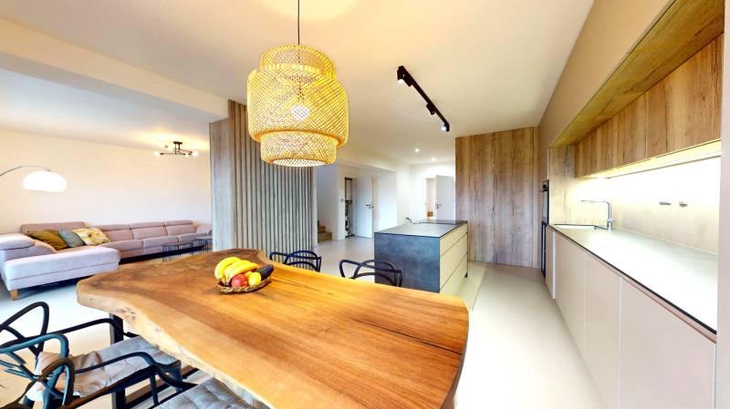 Eine Küche in einem Einfamilienhaus mit einem Holztisch, einem Sofa und moderner Beleuchtung.