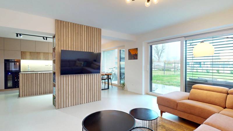 Wohnzimmer mit großen Fenstern, bequemer Couch und Holzwanddekoration.