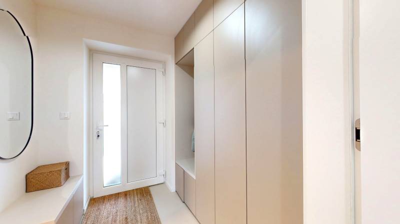 Eingangsflur eines Einfamilienhauses mit einem Garderobenschrank, einem Spiegel und einem Teppich.