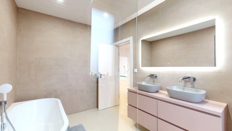 Badezimmer mit Badewanne, zwei Waschbecken und einem Spiegel in einem Einfamilienhaus.