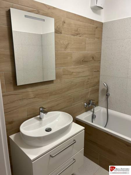 Badezimmer in einer 2-Zimmer-Wohnung mit Holzboden und Badewanne.