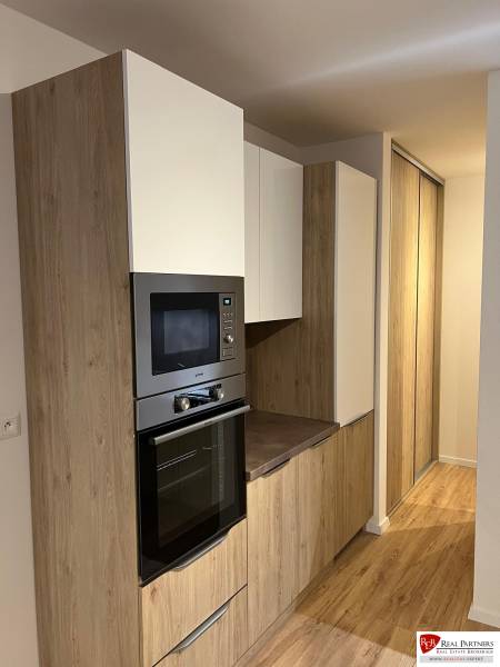 Küchenbereich einer Zweizimmerwohnung mit Holzboden und Einbauschränken.