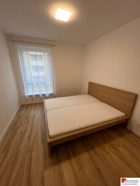 Schlafzimmer mit Bett, Holzboden in einer 2-Zimmer-Wohnung.