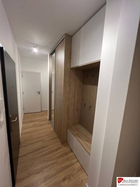 Ein enger Eingangsbereich in einer 2-Zimmer-Wohnung mit Holzboden und Stauraum.