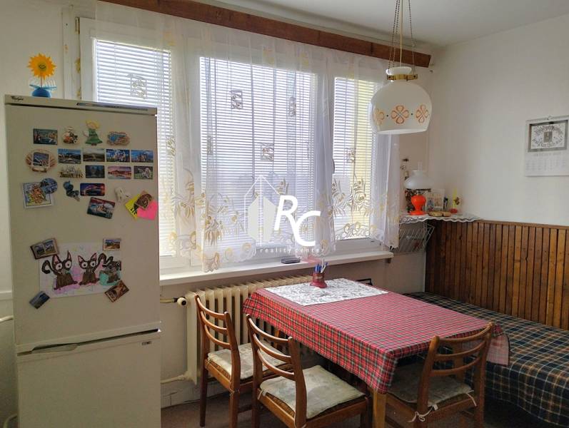 Küche in einer 2-Zimmer-Wohnung mit Esstisch, Stühlen und einem Kühlschrank mit Magneten.