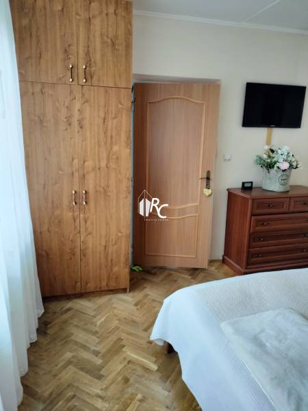 Schlafzimmer in einer 2-Zimmer-Wohnung mit Holzboden, Schrank und Fernseher.