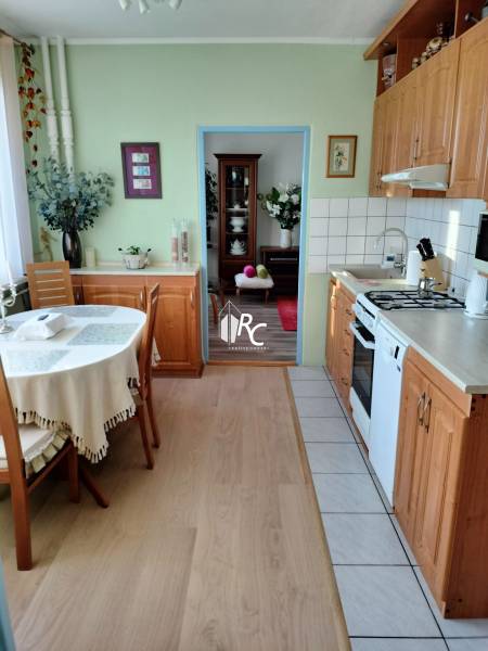 Küche in einer 2-Zimmer-Wohnung mit Holzboden und einem Tisch in der Ecke des Raumes.