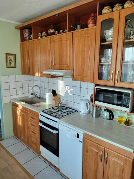 Küche in einer 2-Zimmer-Wohnung mit Holzschränken, Herd und Geräten.