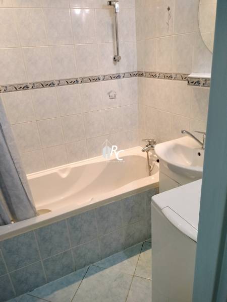 Badezimmer in einer 2-Zimmer-Wohnung mit Badewanne und hellen Fliesen.