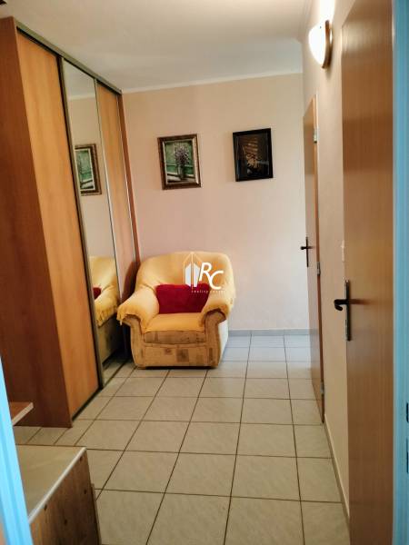 Ein Stuhl bei der Eingangstür mit Fliesenboden in einer Zwei-Zimmer-Wohnung, ein Spiegelschrank.