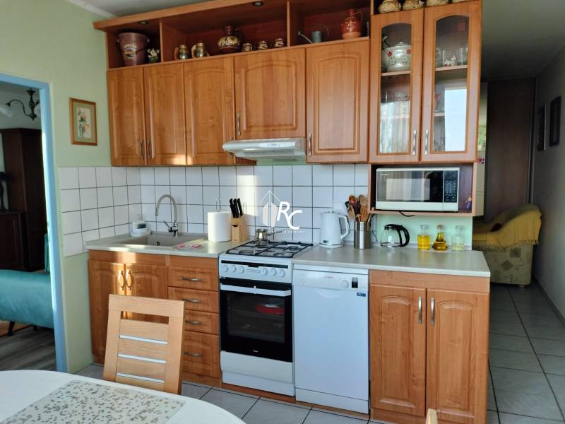 Küche in einer 2-Zimmer-Wohnung mit Holzdekor, ausgestattet mit Geräten und Stauraum.