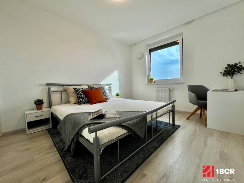 Schlafzimmer in einer 2-Zimmer-Wohnung mit Holzboden und Metallbett.