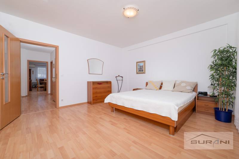 Schlafzimmer in einer 3-Zimmer-Wohnung mit Bett, Kommode und Boden in Holzoptik.