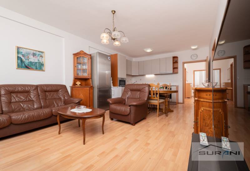 Wohnzimmer mit Ledersofa, Esstisch und Küche, 3-Zimmer-Wohnung, Boden mit Holzdekor.