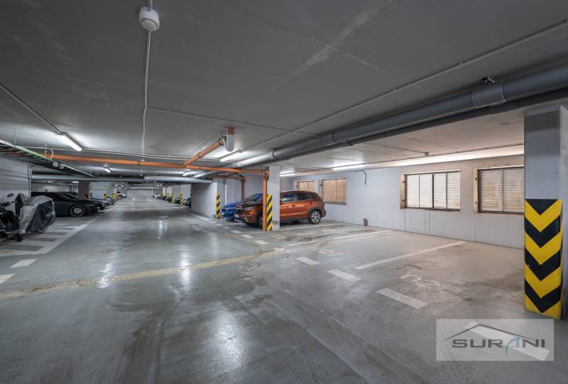 Unterirdischer Parkplatz mit markierten Parkplätzen und geparkten Autos und Motorrädern.