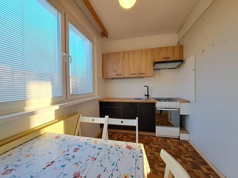 Küche in einer 2-Zimmer-Wohnung mit Holzboden und Esstisch.