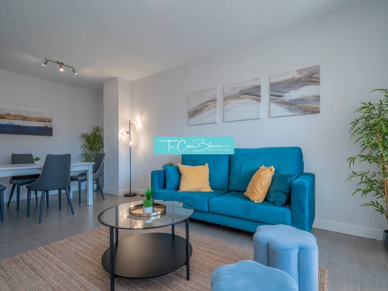 Wohnzimmer in einer 2-Zimmer-Wohnung mit einem blauen Sofa und einem Esstisch.