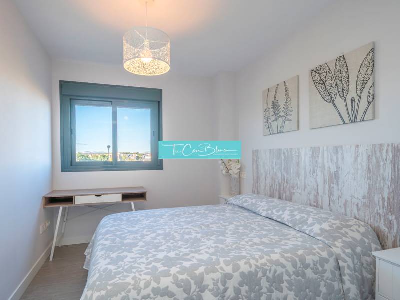 Schlafzimmer in einer 2-Zimmer-Wohnung mit gemustertem Überwurf und Dekorationen an den Wänden.