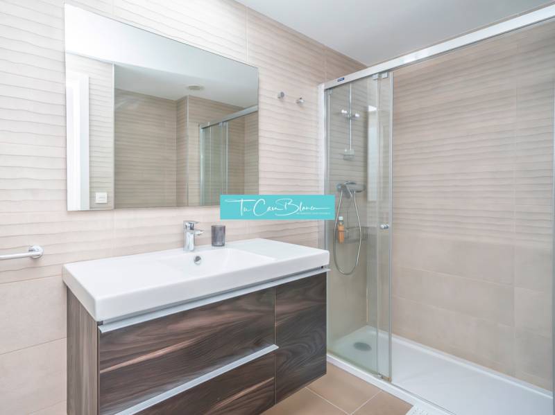 Badezimmer in einer 2-Zimmer-Wohnung mit Duschkabine und Spiegel über dem Waschbecken.