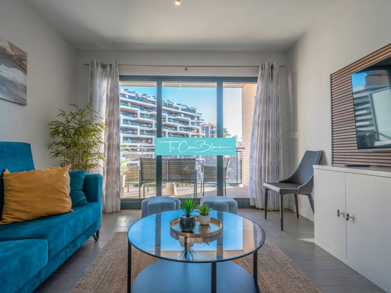 Wohnzimmer in einer 2-Zimmer-Wohnung mit Terrasse, blauem Sofa und Pflanze.