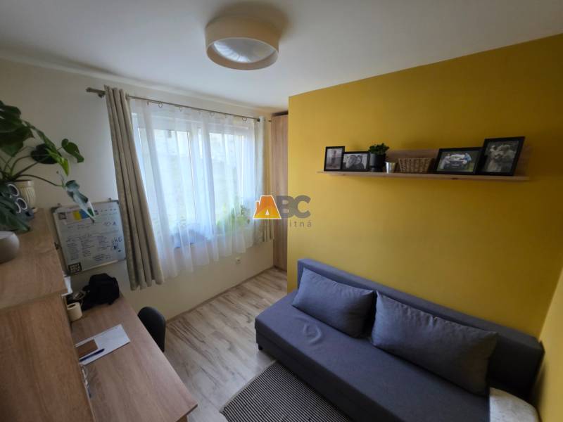 Ein Zimmer in einem Einfamilienhaus mit einem Holzboden, einem Schreibtisch und einem Sofa.