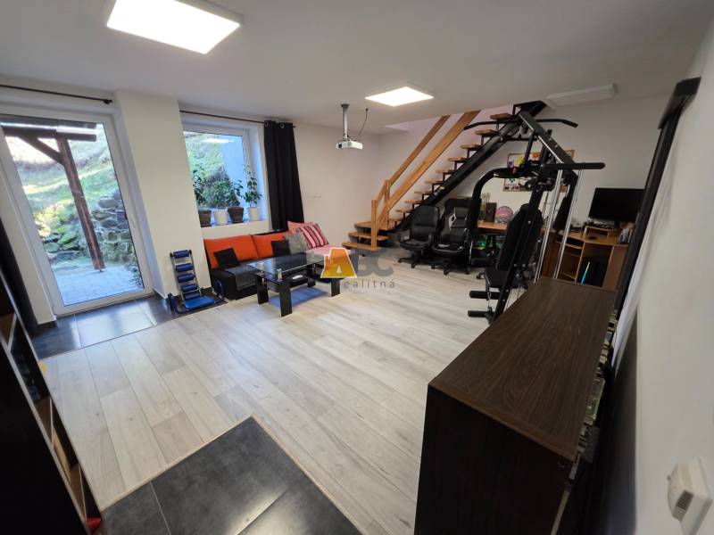 Wohnzimmer in einem Einfamilienhaus mit Holzboden, Fitnessgerät und Treppe.