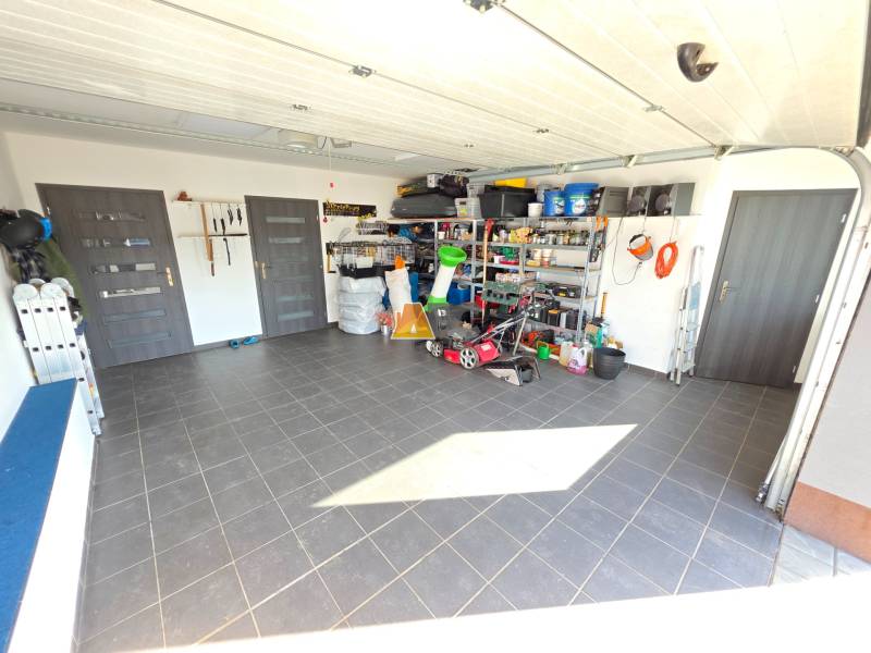 Garage in einem Einfamilienhaus mit Werkzeugen und Lagerregalen, Boden aus Keramikfliesen.