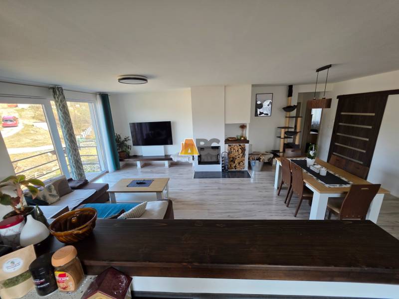 Wohnzimmer in einem Einfamilienhaus mit Sofa, Fernseher und Esstisch auf einem Boden mit Holzdekor.