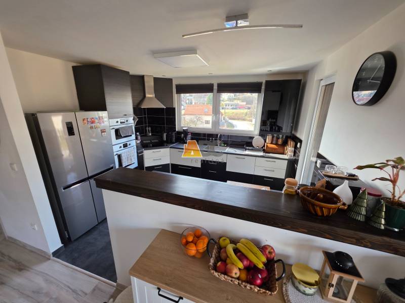 Eine Küche in einem Einfamilienhaus mit modernen Geräten, einer Theke und Obst auf dem Tisch.