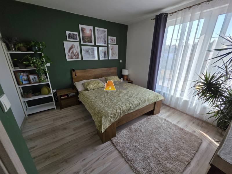 Ein Schlafzimmer in einem Einfamilienhaus mit Holzboden, grüner Wand und Blumen.