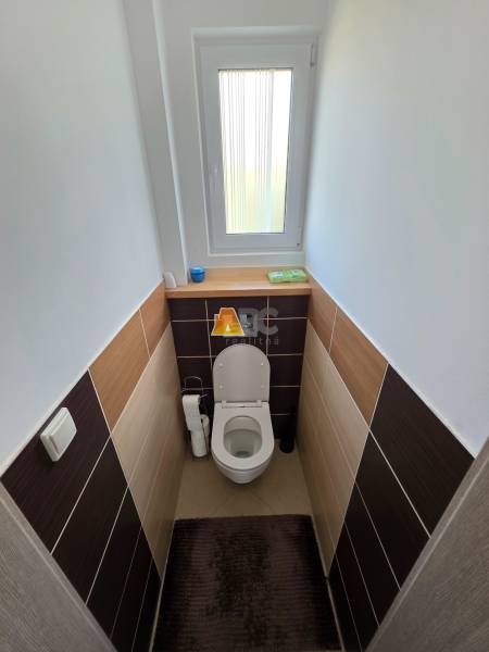 Toilette im Einfamilienhaus mit Fenster und Keramikfliesen, Boden mit Dekor.