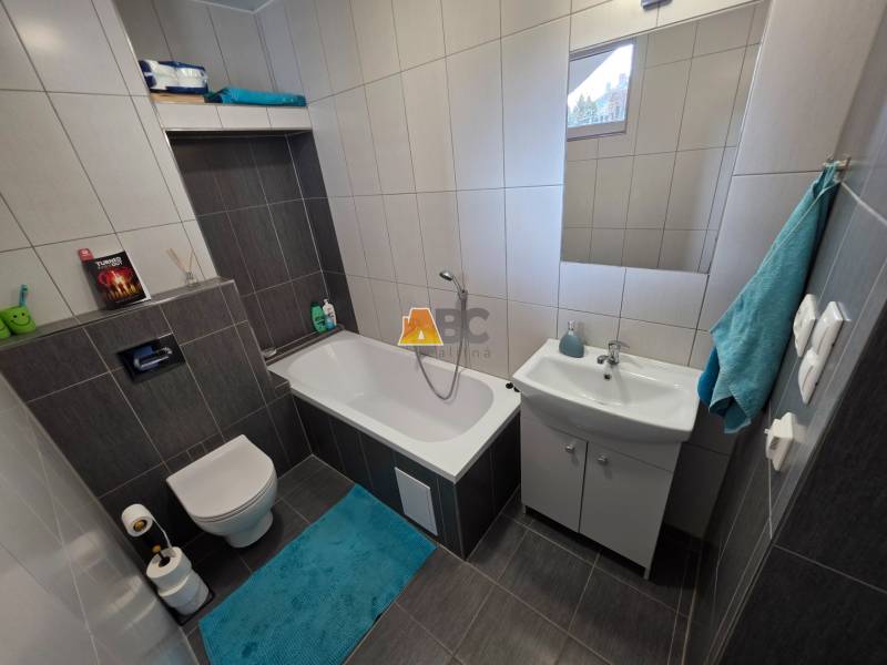 Badezimmer in einem Einfamilienhaus mit Badewanne, Waschbecken und Toilette, Fliesen mit dunklem Dekor.