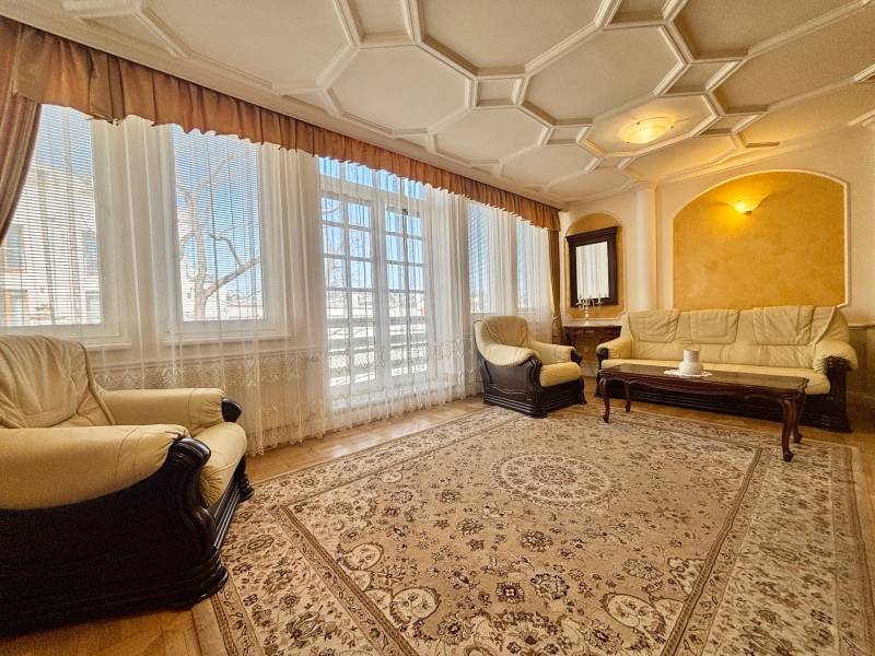 Wohnzimmer in einer 4-Zimmer-Wohnung mit bequemen Sitzgelegenheiten und Teppichen, Boden mit Holzdekor.