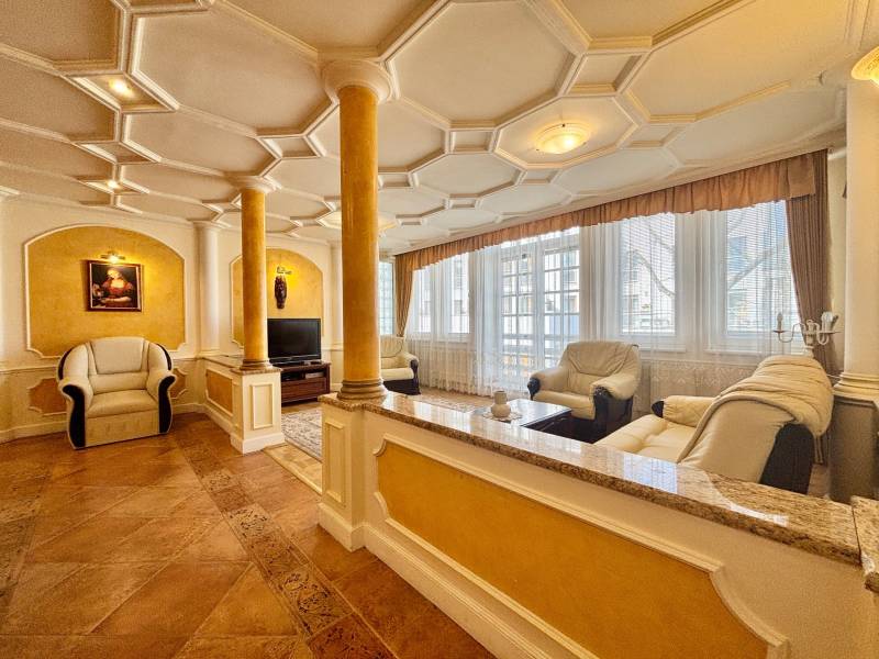 Ein stilvolles Wohnzimmer in einer 4-Zimmer-Wohnung mit Ledersofas, Säulen und einer dekorativen Decke.