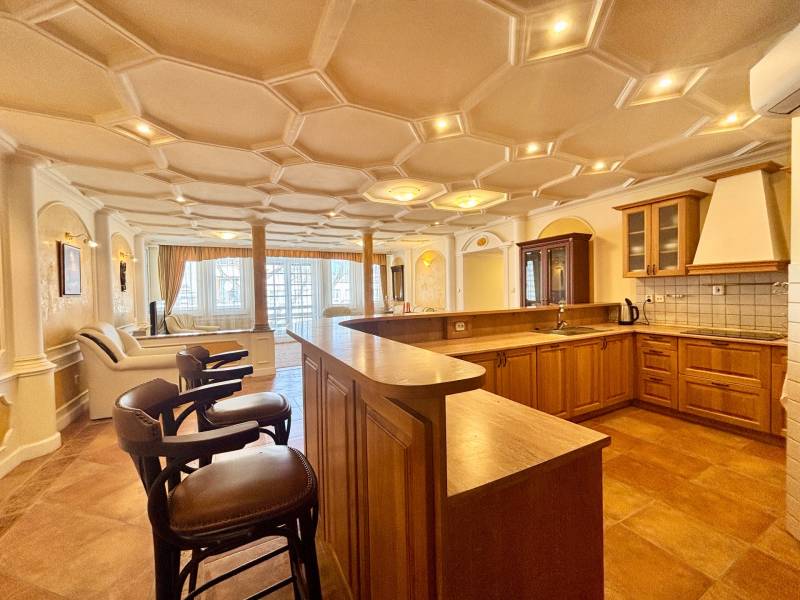 Küche in einer 4-Zimmer-Wohnung mit Holzboden und Barhockern.