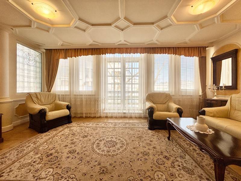 Wohnzimmer mit hellen Sesseln, Teppich und Boden in Holzoptik in einer 4-Zimmer-Wohnung.