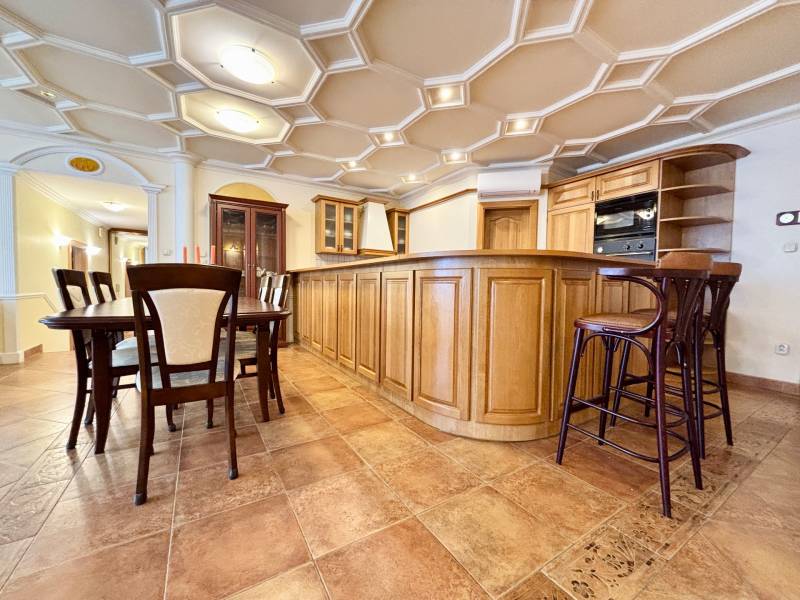 Küche in einer 4-Zimmer-Wohnung mit Esstisch, Holzmöbeln, Fliesenboden und einer interessanten Decke.