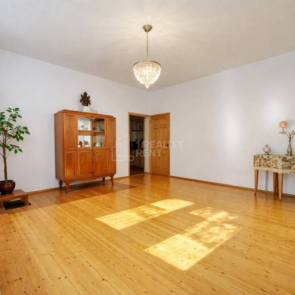 Ein Einfamilienhaus mit einem Kronleuchter, einem Schrank und einem Holzboden in einem geräumigen Wohnzimmer.