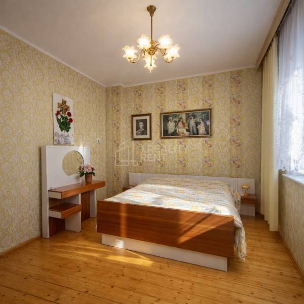 Schlafzimmer in einem Einfamilienhaus mit Holzboden und Blumenmustertapeten.