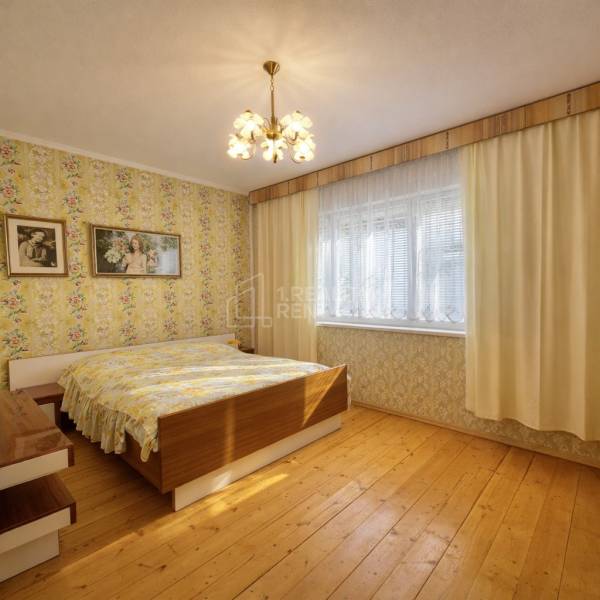 Schlafzimmer im Einfamilienhaus mit Tapeten, Holzelementen und Kronleuchtern.