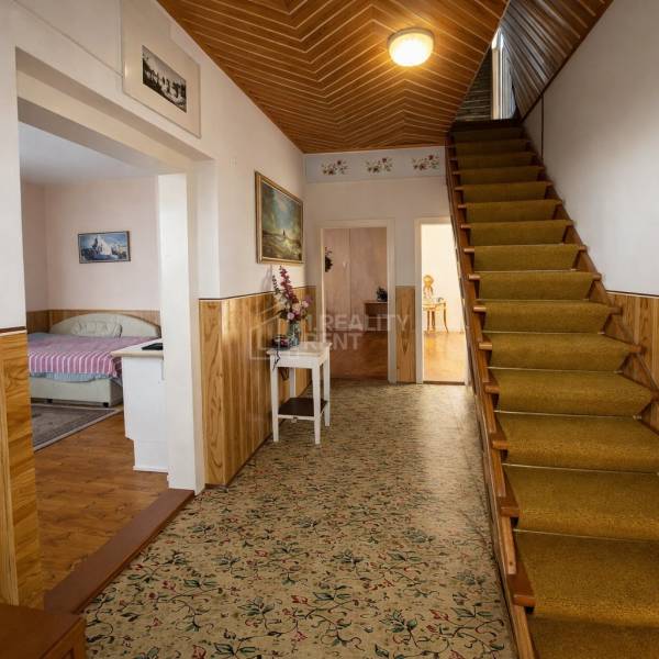 Der Flur eines Einfamilienhauses mit Teppich, Treppe und Bett im nächsten Zimmer.