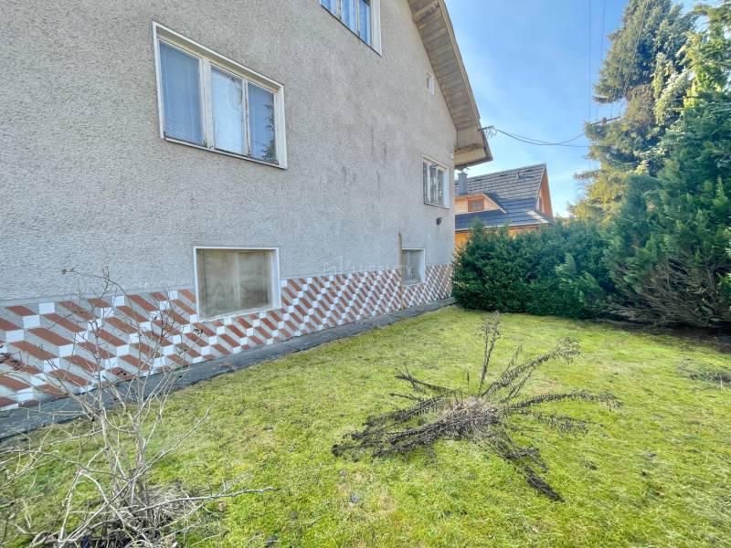 Ein Einfamilienhaus in Terchová mit einem Rasenstück, umgeben von Sträuchern und dekorativem Verkleidung.