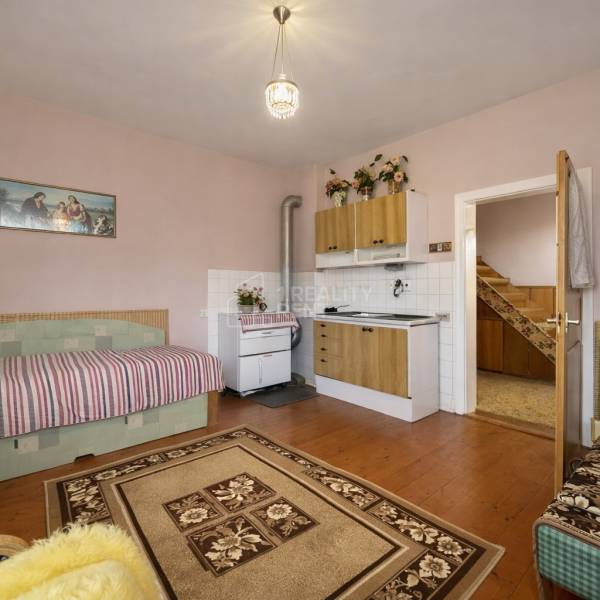 Ein Zimmer mit Küchenzeile, Sofa, Herd und Holzboden in einem Einfamilienhaus.