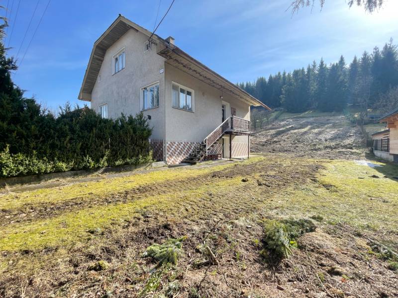 Ein Einfamilienhaus in Terchová mit einem großen Rasenstück, umgeben von Bäumen.