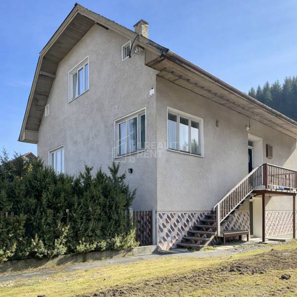 Ein Einfamilienhaus in Terchová mit großen Fenstern, einer Treppe und einem gepflegten Vorgarten.
